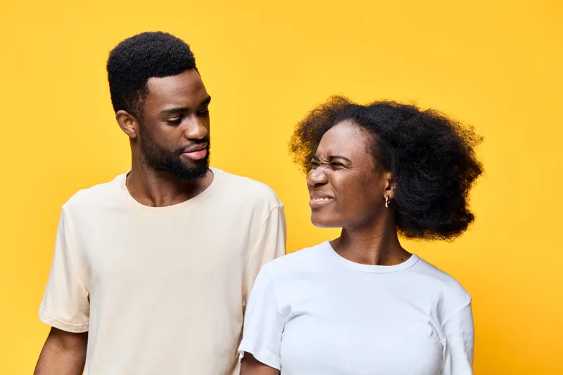 Young African couple smiling and playfully interacting against a vibrant yellow background, exuding joy and happiness, perfect for lifestyle themes