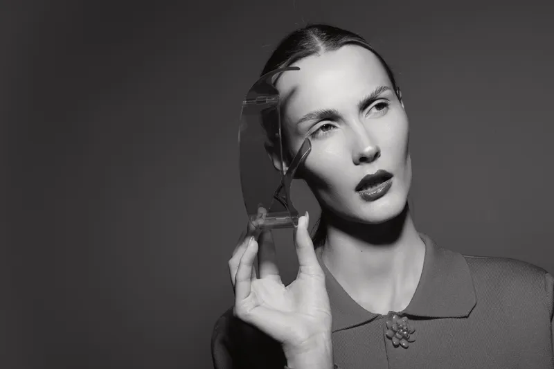 Portrait of a young white woman with pale skin holding an hourglass near her face, dressed in vintage style. Concept for time, patience, and reflection in monochrome.