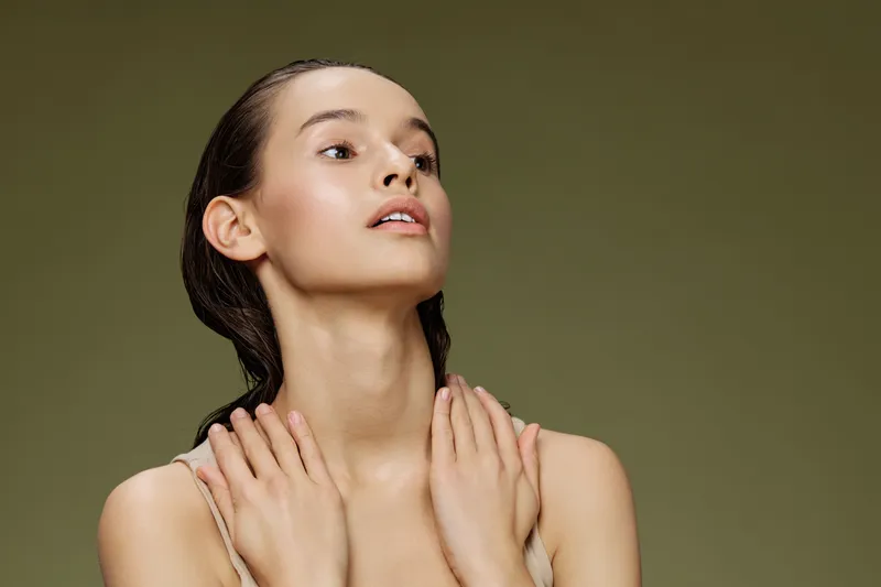 Elegant young woman with a fresh look against a green background, showcasing natural beauty, graceful pose, and subtle emotions for wellness and beauty concepts