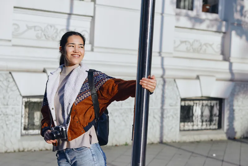 woman street outdoors backpack smiling pole urban casual daylight travel, candid lifestyle city vibe and exploration