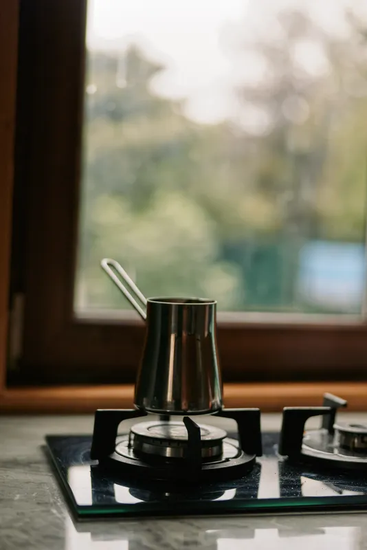 Close up of a metal pot on a gas stove in a modern kitchen, steam rising gently, warm natural light, clean countertops, a calm home cooking moment.