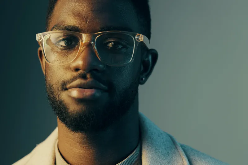 Portrait of a young Black man wearing stylish glasses, showcasing confidence and approachability, ideal for diversity and fashion concepts