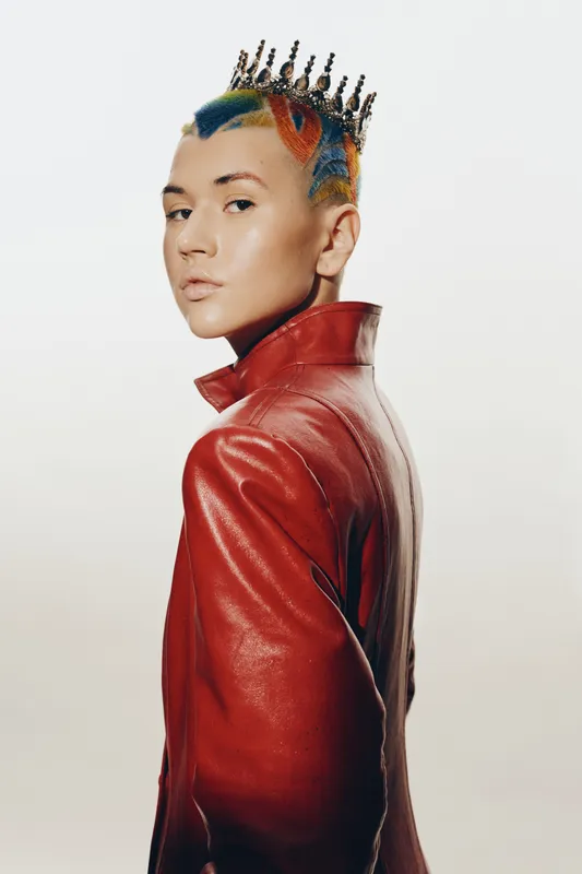 woman with colorful hairstyle and crown wearing a red leather jacket, stylish and edgy fashion portrait with smooth skin and neutral background