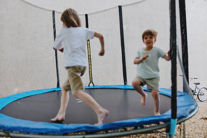 Joyful children jumping on a trampoline, showcasing energy and playfulness in a sunny outdoor setting, creating moments of happiness and fun.