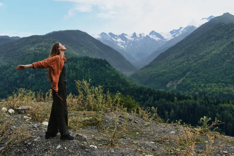 Mountains woman nature freedom authenticity inclusivity standing on ridge with outstretched arms enjoying alpine valley view clothing adventurous outdoor lifestyle