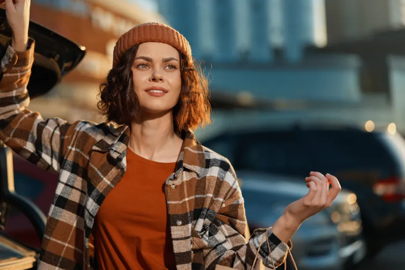 Woman smiling by car in city during golden hour, candid lifestyle portrait with authenticity, mindful living and emotional storytelling creating warm modern urban atmosphere.