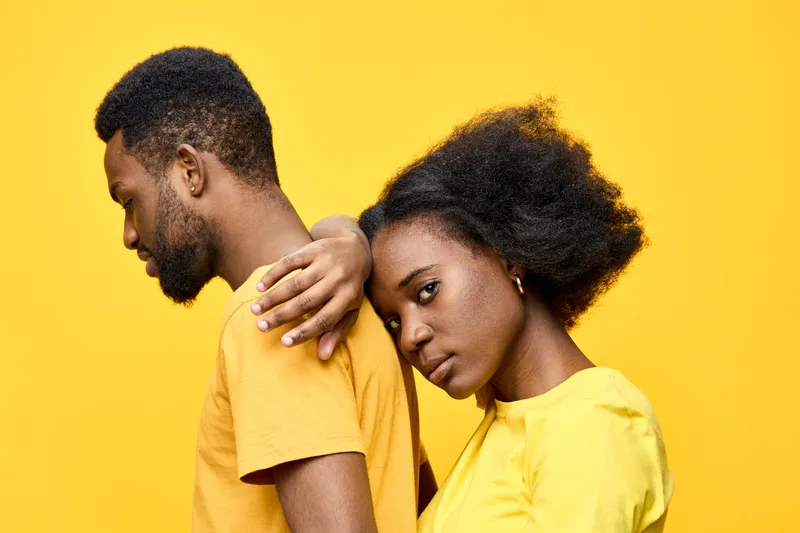 A couple in matching yellow outfits exuding strong emotions against a vibrant yellow backdrop, showcasing love and connection in a contemporary style