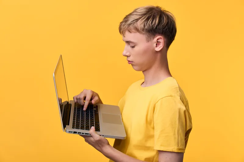 Laptop use, young man in yellow t shirt exploring digital tasks on screen, focused expression, modern tech scene, bright studio lighting, minimalist setup, productivity vibe for online learning and