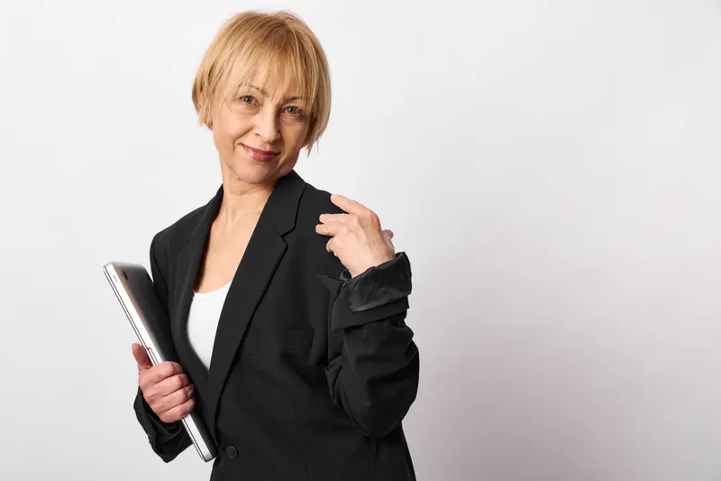 Senior woman in black blazer holding tablet, smiling at camera on white background, Business portrait about technology, communication, confidence today