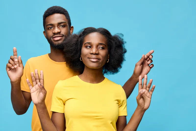 Happy young couple with vibrant outfits posing against a blue background, showcasing joy and connection Bright colors and playful expressions represent a cheerful vibe