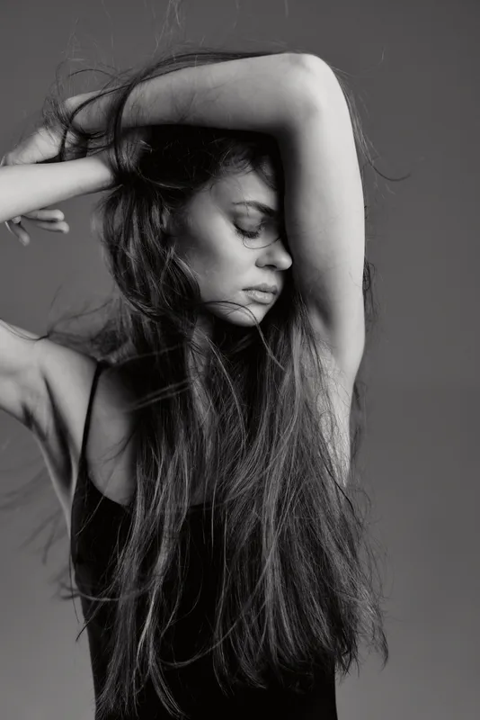 Black and white portrait of a woman with long hair posing gracefully with closed eyes