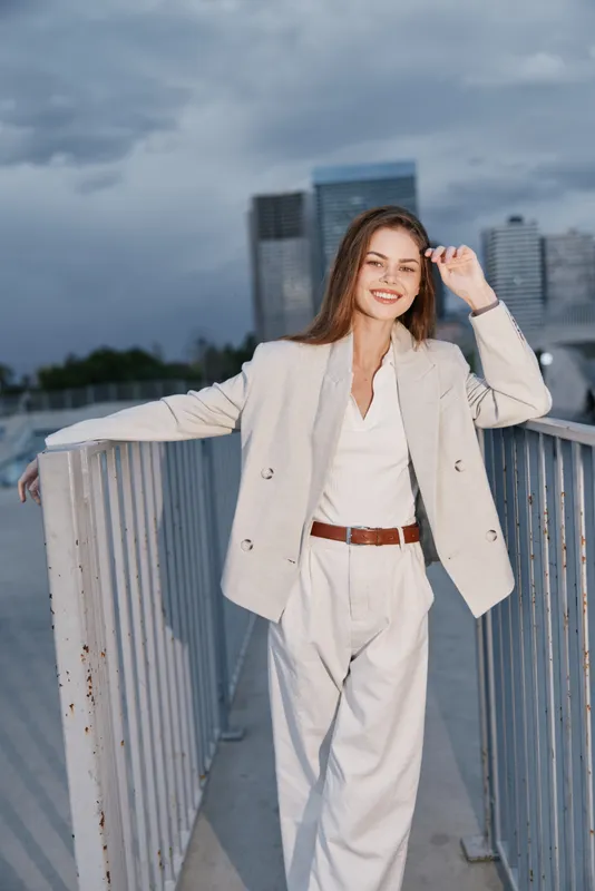 Young woman in beige business suit smiling confidently outdoors urban background business fashion confident woman