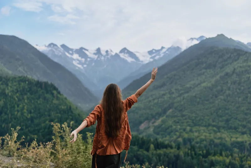 Person on mountain trail, nature and hiking with raised arms for freedom authenticity inclusivity in outdoor landscape and travel