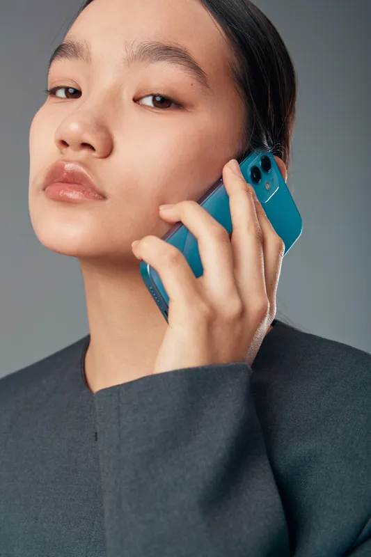 Young woman holding smartphone to ear in closeup portrait with natural makeup and sleek hairstyle. Modern communication, technology use and personal connection on mobile device with calm expression.