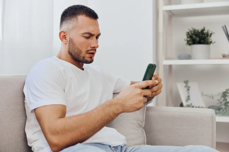 A focused man engaging with his smartphone, representing digital detox and the blurred lines between personal and work life in today’s connected world.