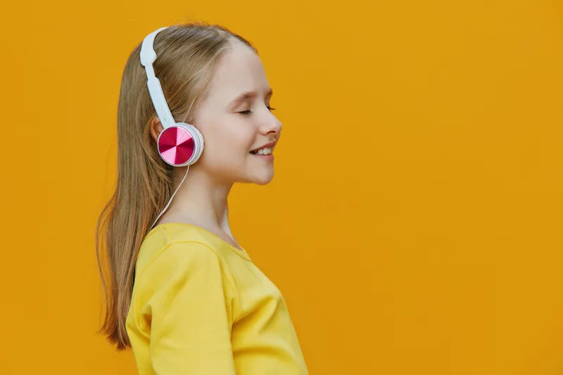 Happy girl enjoying music with headphones on a bright yellow background, embodying joy and relaxation in a vibrant, cheerful atmosphere