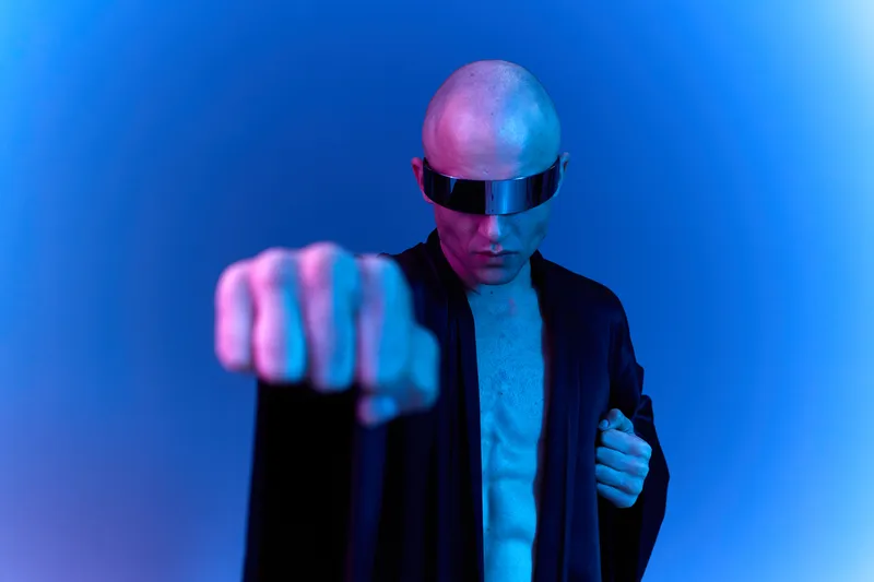 Black and white image of a man wearing futuristic sunglasses, showcasing confidence and strength with a powerful pose and dramatic lighting.