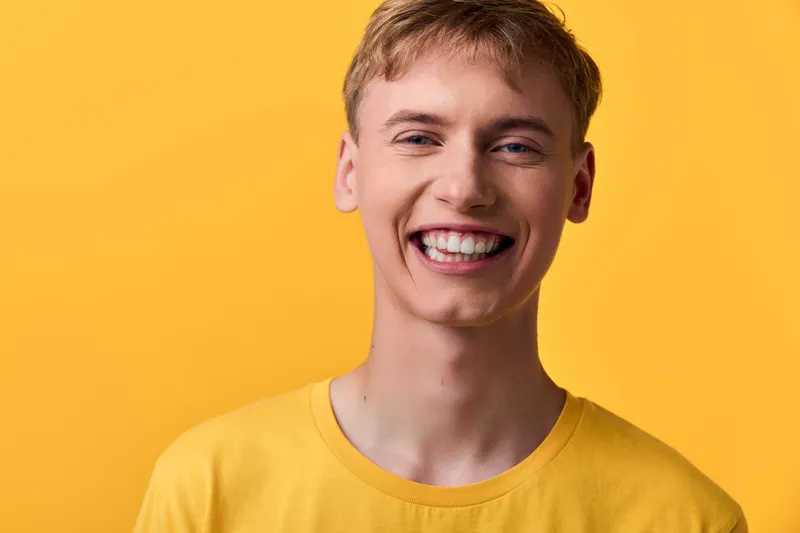 Smiling man in a bright yellow shirt against a vibrant yellow background, conveying warmth, positivity, and approachability for lifestyle, fashion or advertising campaigns in studio setting