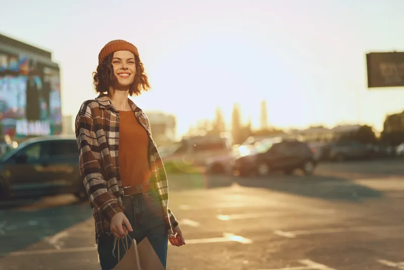 Woman smiling while shopping in an urban street at golden hour, a candid lifestyle portrait capturing authenticity, golden hour glow, mindful living and emotional storytelling.