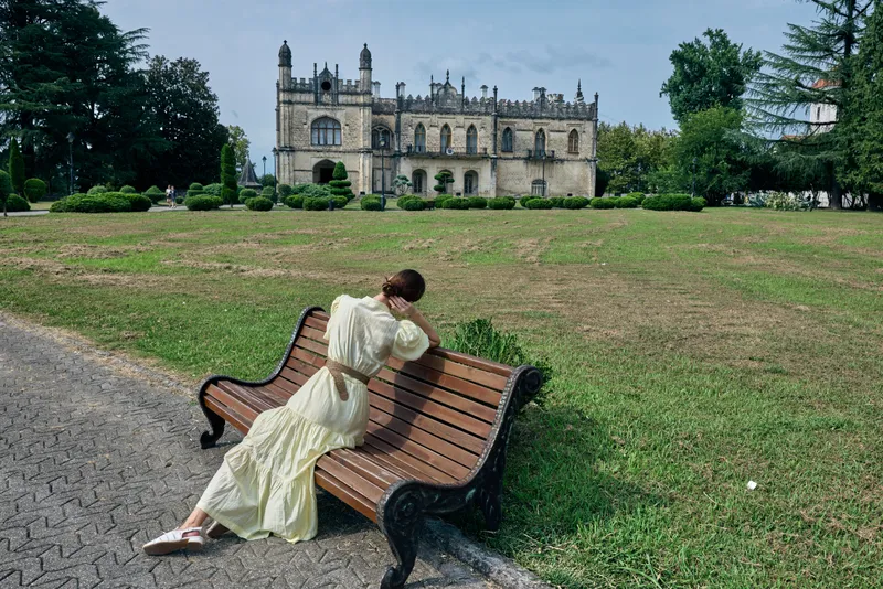 woman on bench in park near historic manor, authentic inclusive