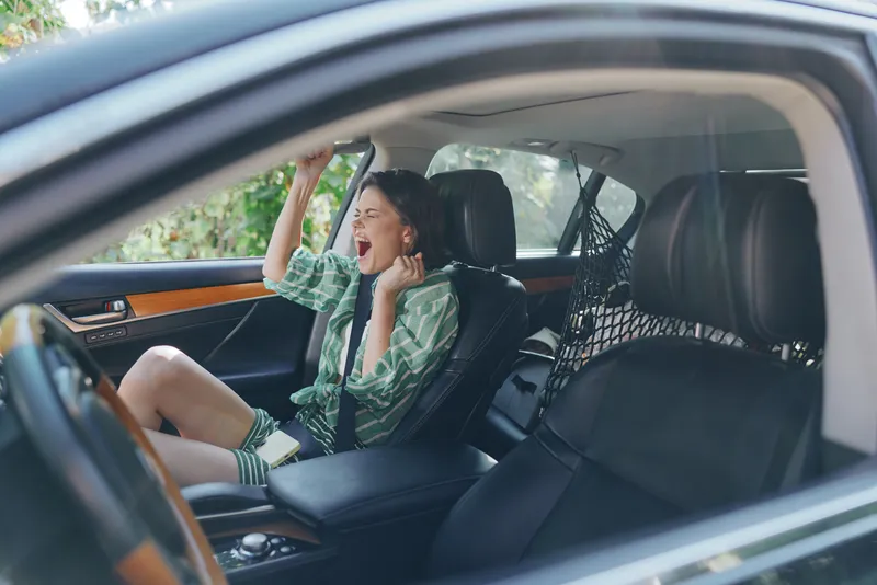 Car, child, excited, a cheerful child sits in the back seat with arms raised, enjoying a playful ride inside a warm car interior, conveying joy and anticipation.