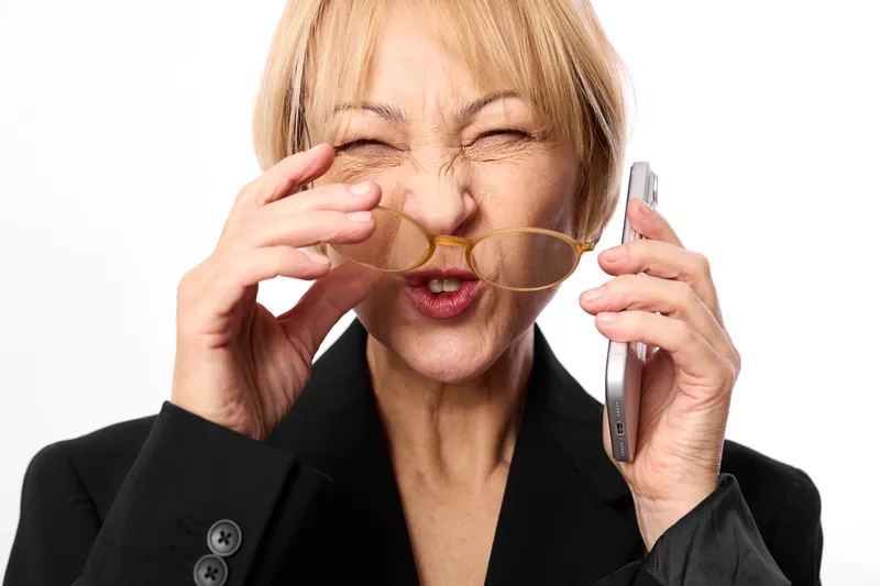 Woman elderly business mask phone smartphone communication disguise laughter portrait, she holds gold mask and talks on cell phone, white studio background