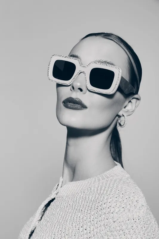 Portrait of a pale skinned caucasian woman with slicked back hair wearing large square sunglasses and hoop earrings. Fashion concept with modern style and confident expression.