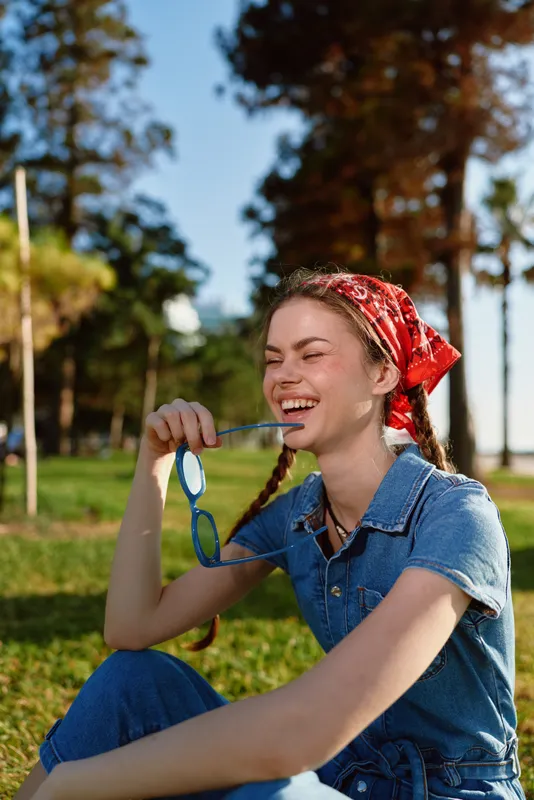 lifestyle woman in modern boho-western denim street style laughing outdoors with red bandana and vibrant film color tones during sunny day