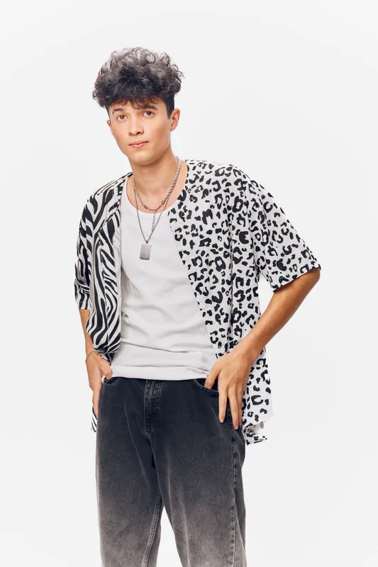 young man wearing patterned shirt with black and white animal prints, casual style clothing, standing confidently on plain white background