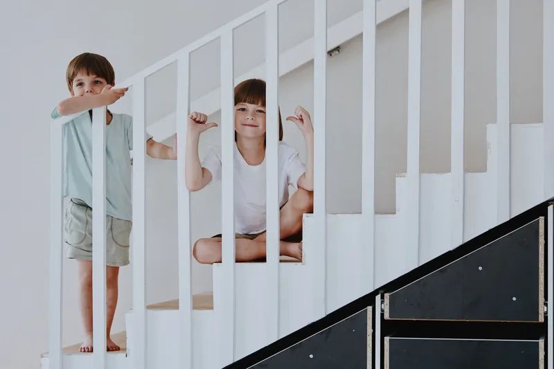Two happy boys play on the staircase, showcasing their playful spirit with laughter and joy, emphasizing childhood innocence and exploration.