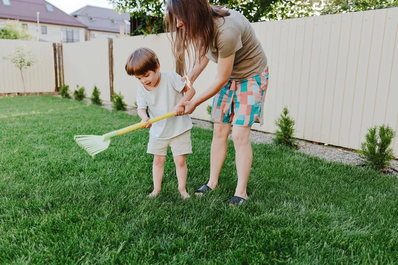 Loving woman playing with her child in the garden, enjoying outdoor activities, and creating joyful memories together in a bright, sunny environment.