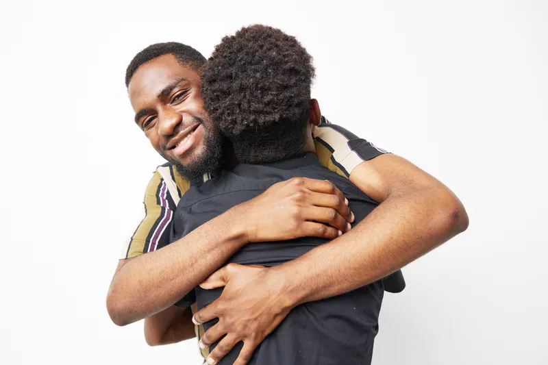 Warm embrace between a black man and a child, showcasing love and connection, evoking feelings of happiness and togetherness in a bright setting.