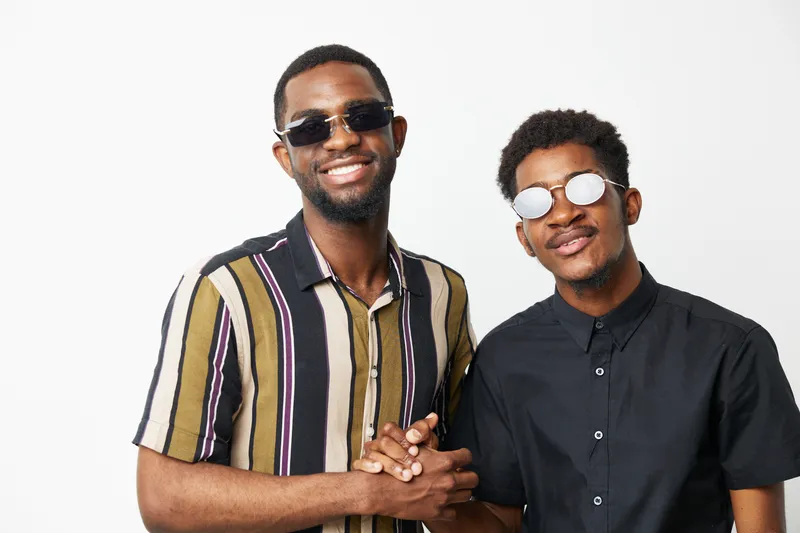Stylish black men posing together, showcasing camaraderie and joy with trendy sunglasses. Capturing a vibrant and youthful spirit in contemporary fashion.