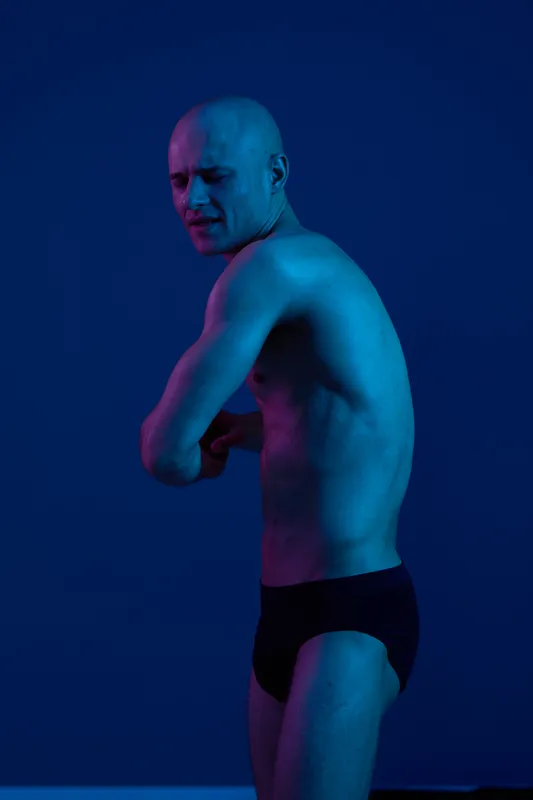 A striking black and white image capturing a man in a dynamic pose, conveying strength and emotion against a dark backdrop.