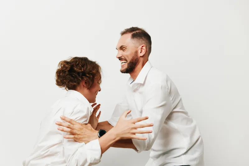 Professional man in a business setting shares a warm moment on a clean, isolated colored background, conveying confidence, collaboration, and upbeat emotion today.