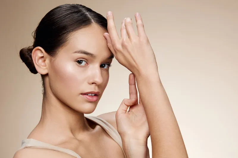 Elegant portrait of a young woman with a natural look, showcasing graceful hand movements and soft lighting, perfect for beauty and wellness themes