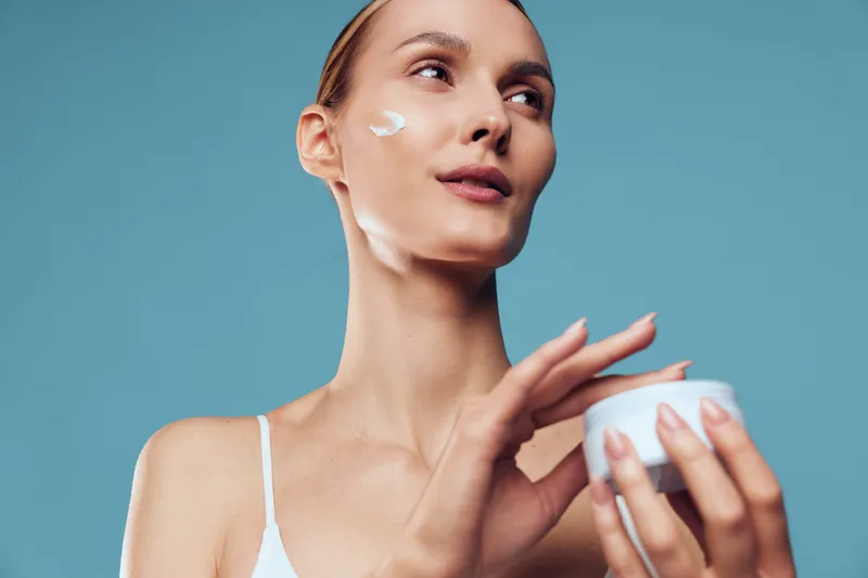 Woman skincare beauty mask on face with cream and serum for hydration, pampering selfcare in a clean studio portrait on blue background, calm wellness personal grooming for healthy glow