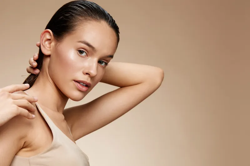 Elegant portrait of a young model with a neutral background, showcasing natural beauty, fashion style, and a serene expression emphasizing a minimalist aesthetic