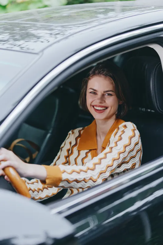 Car, driver, woman, smile a cheerful woman sits in the driver's seat with her hand confidently on the steering wheel, radiating joy, energy, and readiness for a new journey