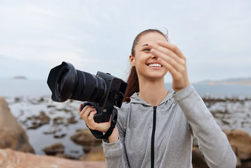 Young woman enjoying photography at the beach with a camera, exuding joy and passion while capturing precious moments in nature