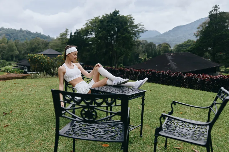 Athletic young woman relaxing outdoors in sporty attire, representing fitness and wellness with a serene mountain backdrop and a fresh, natural atmosphere
