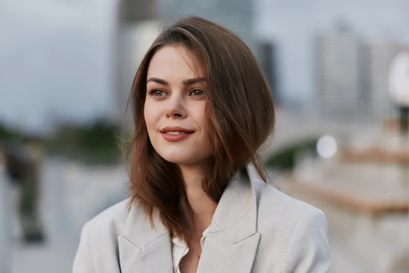 young woman in gray business suit with confident smile outdoors urban background fashion business style