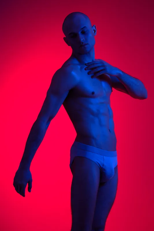 A man poses dramatically in a striking light composition, conveying strong emotions with vibrant blue and red colors, offering a powerful visual impact.