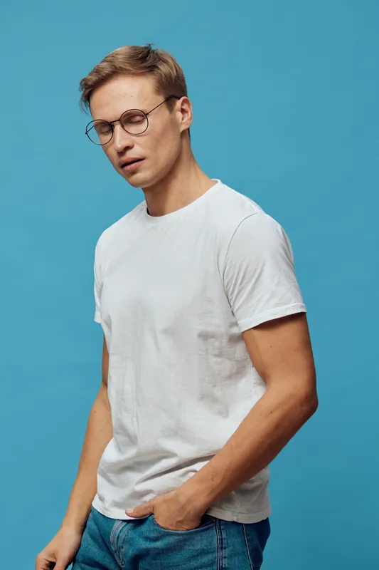thoughtful young man wearing glasses white t-shirt blue jeans studio portrait digital detox mental health concept isolated blue background