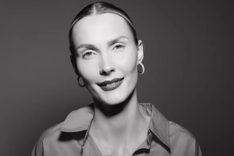 Close-up portrait of a smiling Caucasian woman with pale skin and sleek hair in studio. Concept of happiness, confidence, and natural beauty with soft lighting.
