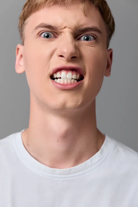 Angry intense expression with clenched teeth and raised eyebrows, studio closeup of a male face conveying frustration, stress, and dramatic mood for bold emotional storytelling