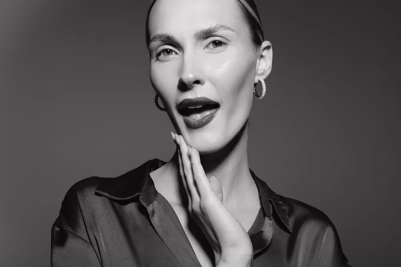 Portrait of a white woman with light skin and slicked hair posing with hand on cheek in studio. Concept of beauty and elegance.