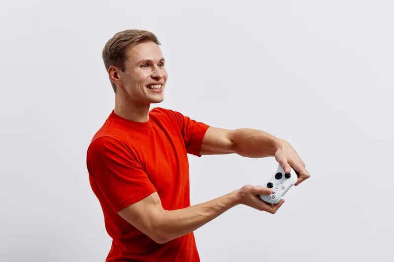 Smiling man taking selfie with smartphone, casual red t-shirt, happy expression, isolated on plain white background, studio portrait, people lifestyle concept, cheerful, youthful, modern, technology, 