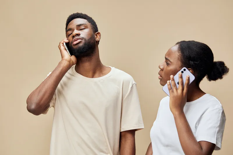 A couple engaged in a thoughtful conversation over the phone, reflecting emotions of connection and communication in a neutral toned setting
