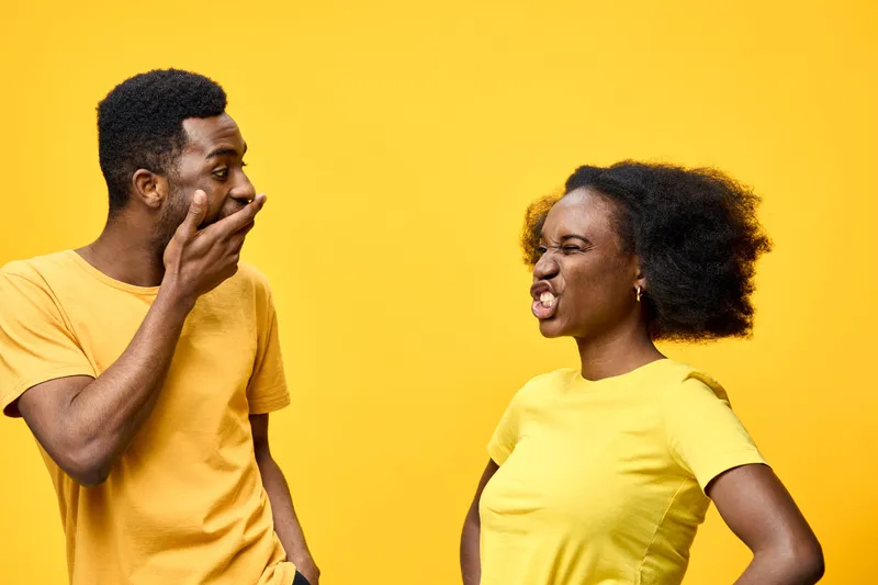 Joyful couple laughing and sharing a playful moment against a vibrant yellow background, showcasing their trendy yellow outfits and expressive emotions
